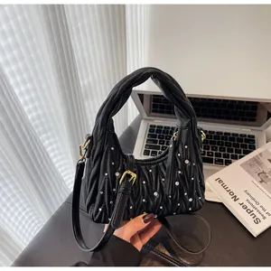 Detail view of black pleated dumpling bag with pearl accents and knotted handle