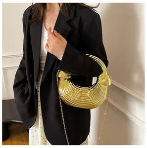 Chic gold metallic crescent bag with knotted handle shown on model in modern setting