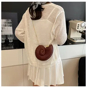 Détail d'un sac bandoulière en acrylique marron en forme de conque avec chaîne dorée