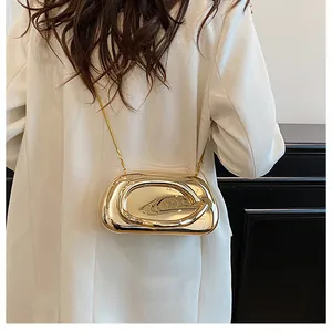 Modern gold metallic evening clutch bag with chain strap styled on a white blazer