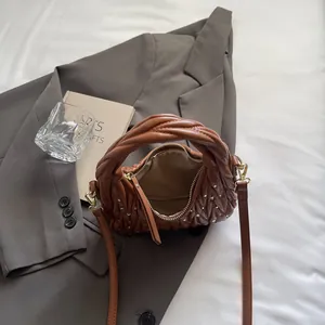 Detail of brown pleated quilted bag with crystal accents and twisted handle in a lifestyle setting