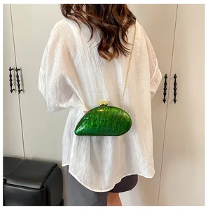 Fashionable green acrylic evening clutch with gold chain shown on a model's back