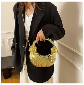 Detailed view of golden semi-circular textured handbag with metallic finish and round handle
