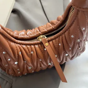 Detail of quilted brown leather bag featuring sparkling rhinestones and gold zipper hardware