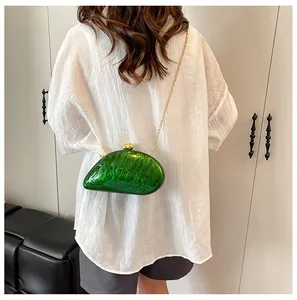 Macro shot of green acrylic shell-shaped clutch with marble texture and gold chain