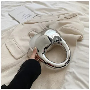 Detail der silbernen Acryl-Abendtasche mit rundem Griff und eleganter Metallkette