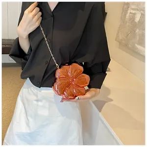 Modella che indossa una mini borsa a fiori 3D con finitura metallica lucida e catena d'oro