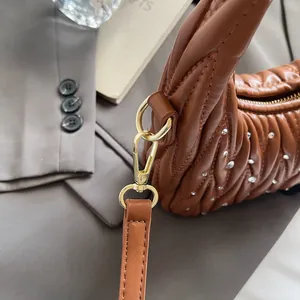 Detail of brown pleated leather bag with silver studs and gold metal clasp