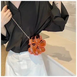 Dettaglio di una borsa a tracolla a forma di fiore metallico con catena dorata