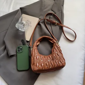 Detail of brown pleated leather bag with small rhinestones and adjustable strap