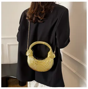 Detail of the golden metallic crescent bag with unique knot handle and chain strap