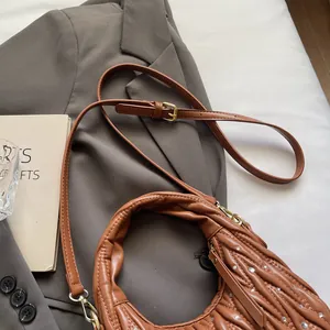 Detail of caramel brown ruched bag with rhinestones on a stylish grey blazer background