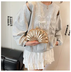 Detail of rose gold shell evening bag with radial texture and bead clasp held by model