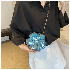 Primo piano di una mini borsa floreale 3D con finitura blu metallizzato e catena d'oro
