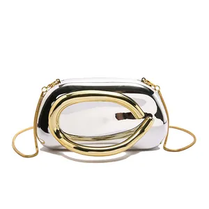 Detail of silver capsule clutch bag with polished metal surface and golden chain strap