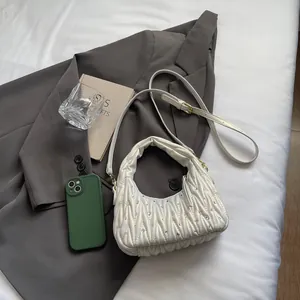Close-up of white matelassé handbag with rhinestones placed on a gray blazer