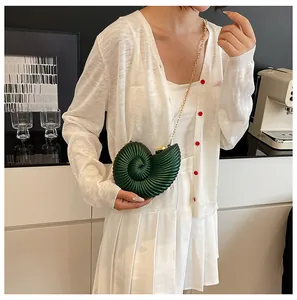 Gros plan du sac coquille nautile vert foncé avec chaîne dorée sur un mannequin femme