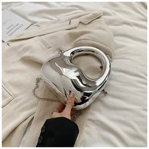 Nahaufnahme einer silbernen Acryl-Handtasche mit Kette auf beigem Cordstoff-Hintergrund