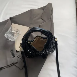 Detail of black pleated bag with rhinestone accents, twisted handle and gold zipper