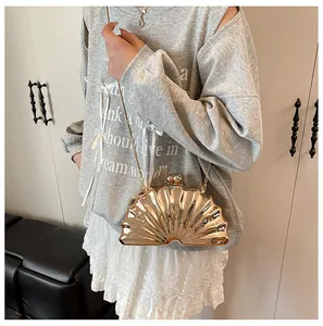 Close-up of golden shell-shaped evening bag with metallic texture and chain strap