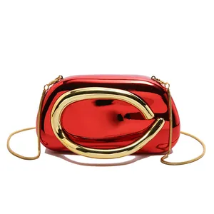 Detail view of a luxury red metallic evening clutch with a bold gold handle and chain strap