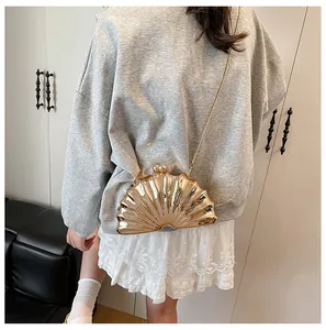 Close-up of shell-shaped gold evening bag with metallic mirror finish and chain strap