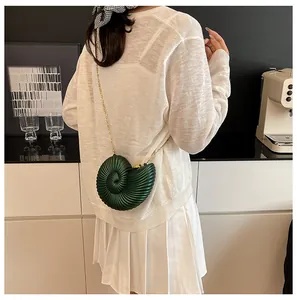 Détail du sac coquillage en acrylique vert foncé avec bandoulière chaîne dorée