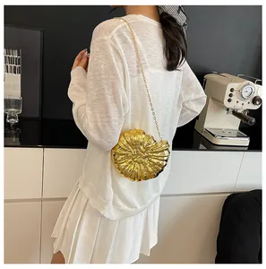 Schicke goldene Abendtasche in Muschelform mit feiner Kette, getragen am Rücken des Models