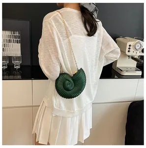 Détail du sac bandoulière en acrylique vert foncé en forme de conque avec chaîne