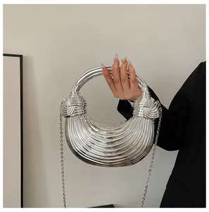 Macro detail of metallic silver pleated handbag with knotted handle and chain strap
