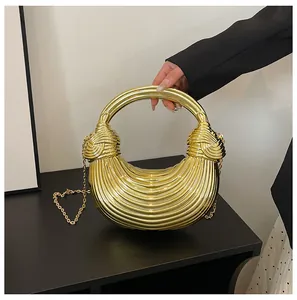 Detail of a gold metallic crescent bag with ribbed texture and circular handle