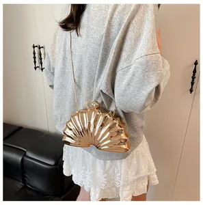 Detail of a golden shell-shaped evening clutch bag with fine embossed textures and chain