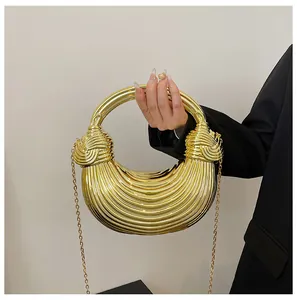 Detail of a crescent-shaped gold metallic handbag featuring pleated textures and knot handles