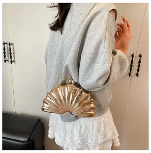 Champagne gold shell-shaped clutch bag with ball clasp and metal chain on a model