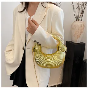 Detail of a golden metallic half-moon bag with vertical stripes and a knotted handle design