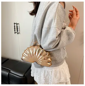 Detail of gold shell shaped acrylic evening clutch bag with metallic chain strap