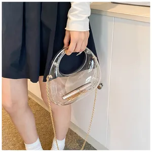 Détail d'une pochette en acrylique transparent avec poignée ronde et chaîne dorée
