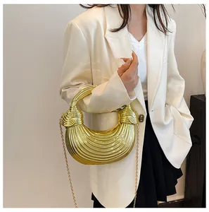 Detailed side view of a gold crescent bag with wavy texture and chain strap worn by model