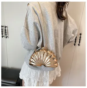 Shell-shaped evening clutch bag in gold finish shown on a model with chain strap