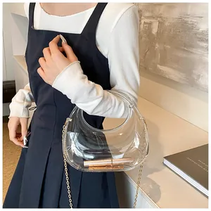 Détail d'un sac demi-lune transparent en acrylique avec chaîne en métal sur table