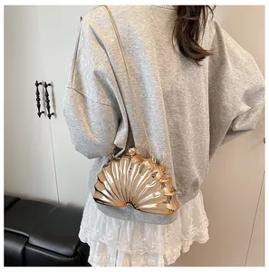 Detailed view of the golden shell-shaped evening bag with metallic finish and chain strap