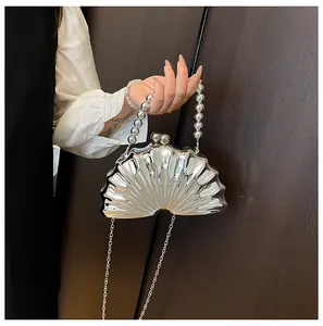 Macro detail of silver seashell evening clutch with bead handle and chain strap