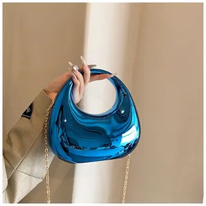 Détail d'un sac à main bleu miroir métallisé avec chaîne dorée et poignée incurvée