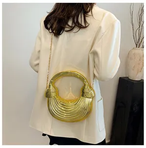 Detailed view of the gold semi-circle clutch bag with textured finish and chain strap