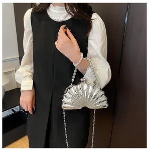Silver shell evening clutch with pearl handle and metal chain shown on a fashion model