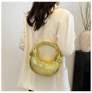 Detail of gold metallic half-moon bag with pleated texture and knot handle on model