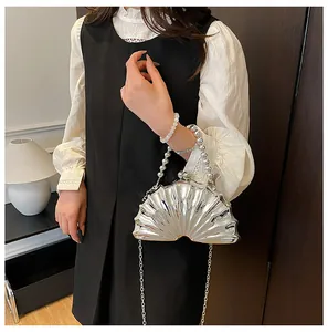 Detail of silver shell-shaped evening bag with pearl handle and metal chain strap