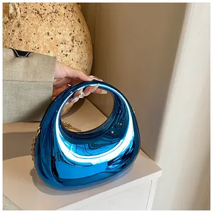 Détail de la pochette en acrylique miroir bleu avec chaîne en métal doré et poignée