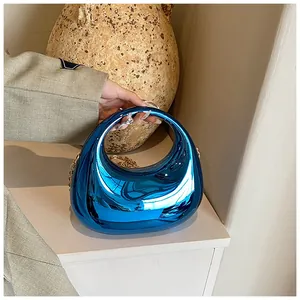 Détail du sac à main bleu vernis en forme de demi-lune avec une bandoulière dorée