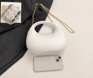 Detailansicht der weißen Tasche mit Goldkette und Handy zum Größenvergleich